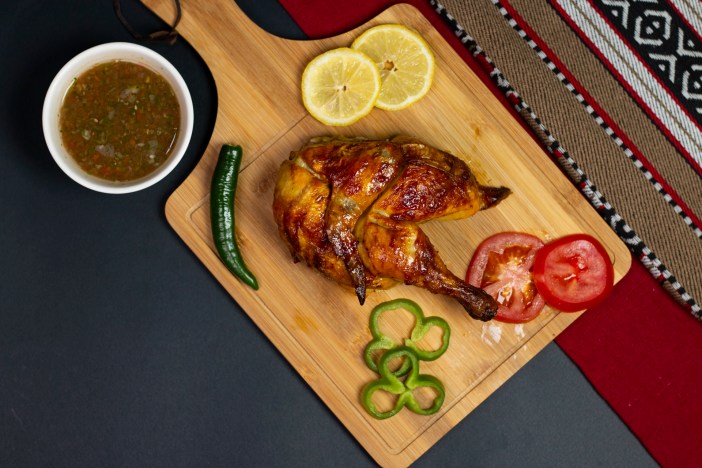 Samarkandi Restaurant's golden roasted chicken: Crispy whole chicken resting on saffron Bukhari rice with toasted almonds and caramelized onions | Fresh parsley garnish | Sitra, Bahrain