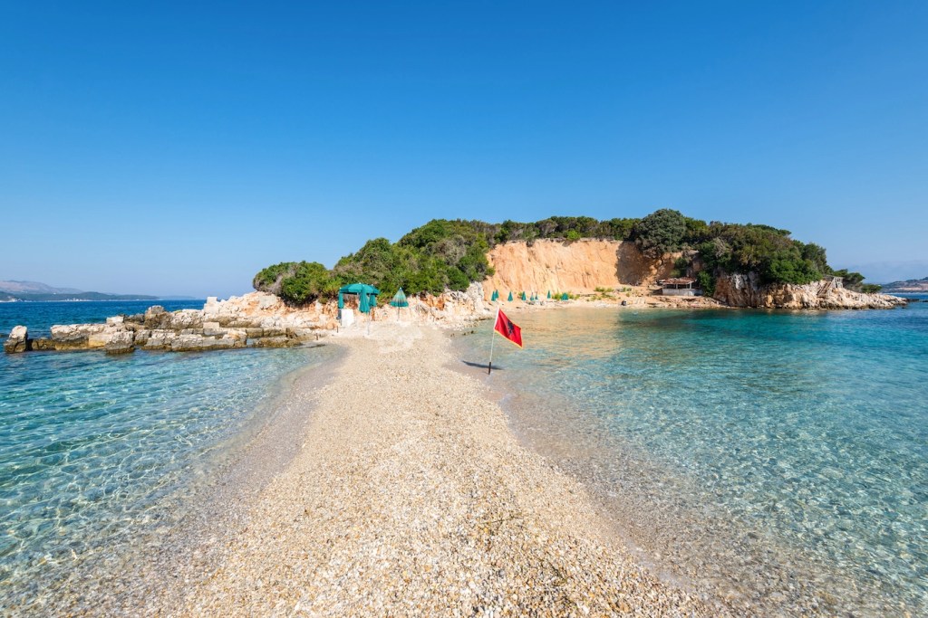 Secluded beach cove with clear turquoise water and rugged cliffs in the Albanian Riviera