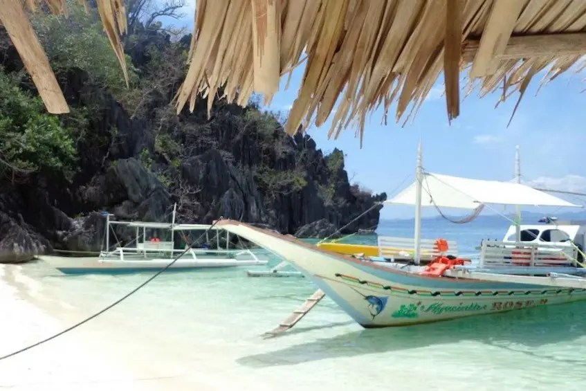 Tour boat anchored near Barracuda Lake and Twin Lagoon with snorkelers exploring Skeleton Wreck in Coron, Philippines