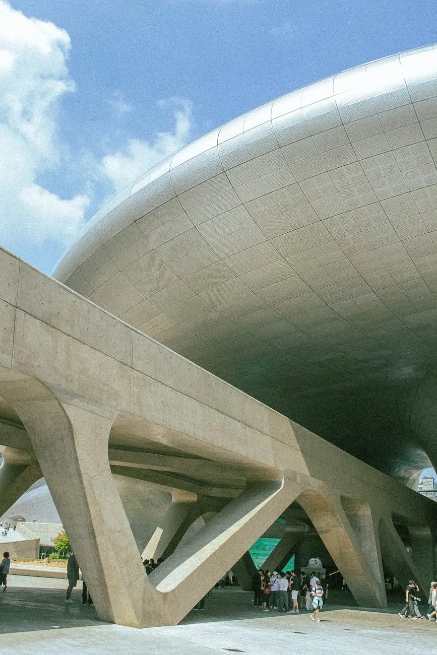 View of the futuristic Dongdaemun Design Plaza (DDP) in Seoul, showcasing its unique architectural design with curved metal roof and supporting concrete pillars.