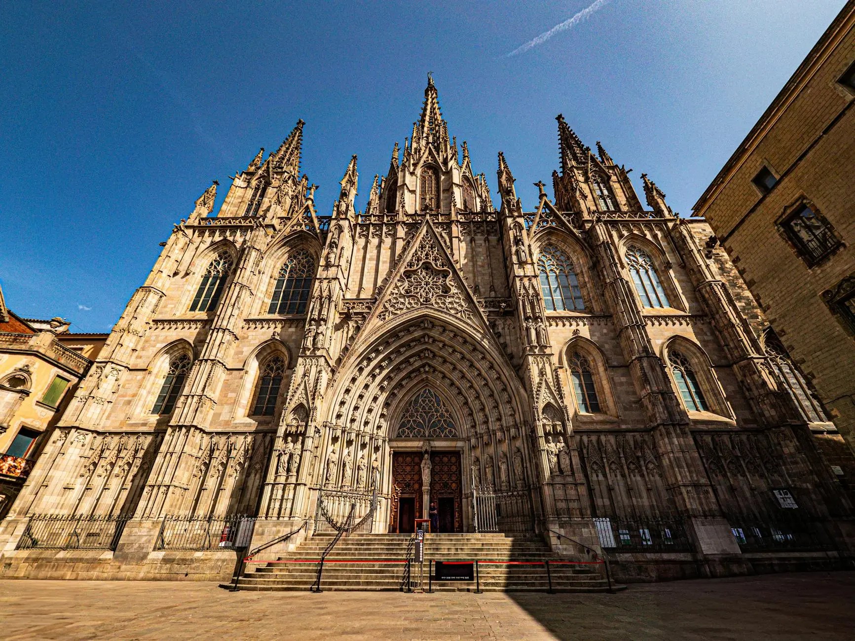 Facade of the ornate Barcelona Cathedral, showcasing intricate Gothic architecture under a clear blue sky.