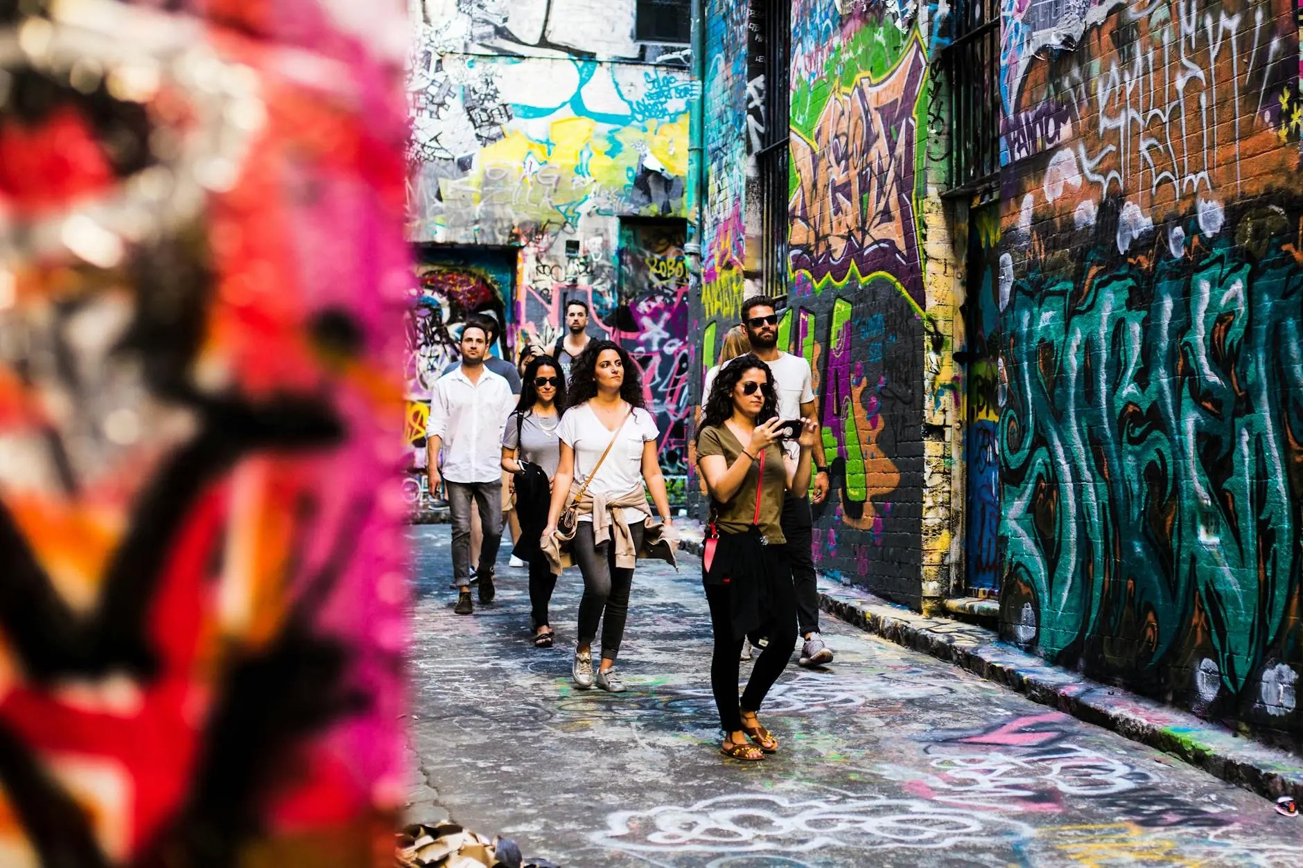 A group of people exploring a vibrant laneway filled with colorful street art in Melbourne.
