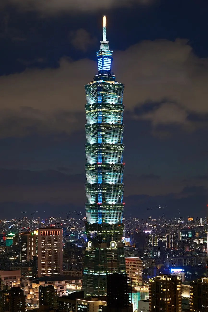 A night view of Taipei 101, illuminated with blue and white lights, towering over the city skyline.