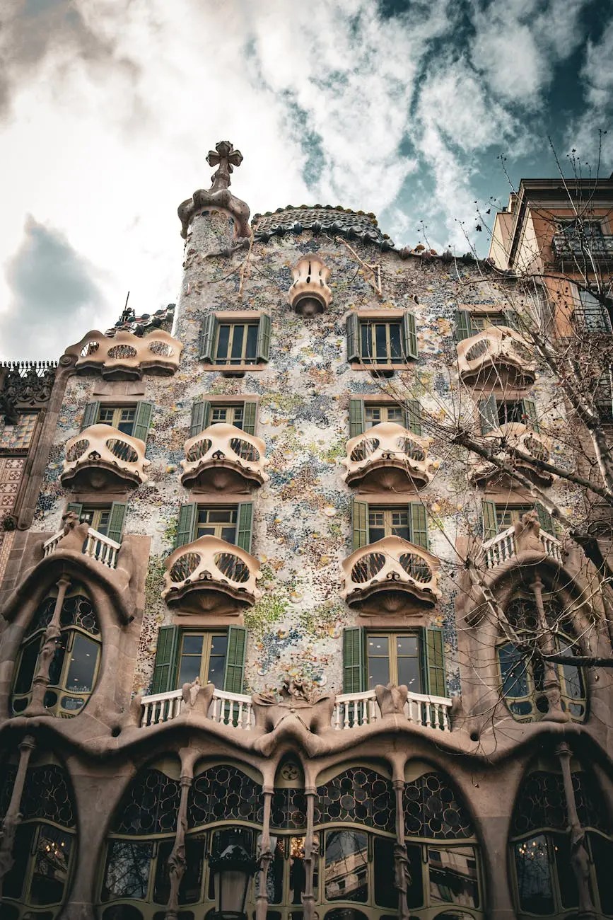 Close-up view of the ornate facade of Casa Batlló, showcasing its colorful tiles, unique architectural details, and distinctive windows against a cloudy sky.