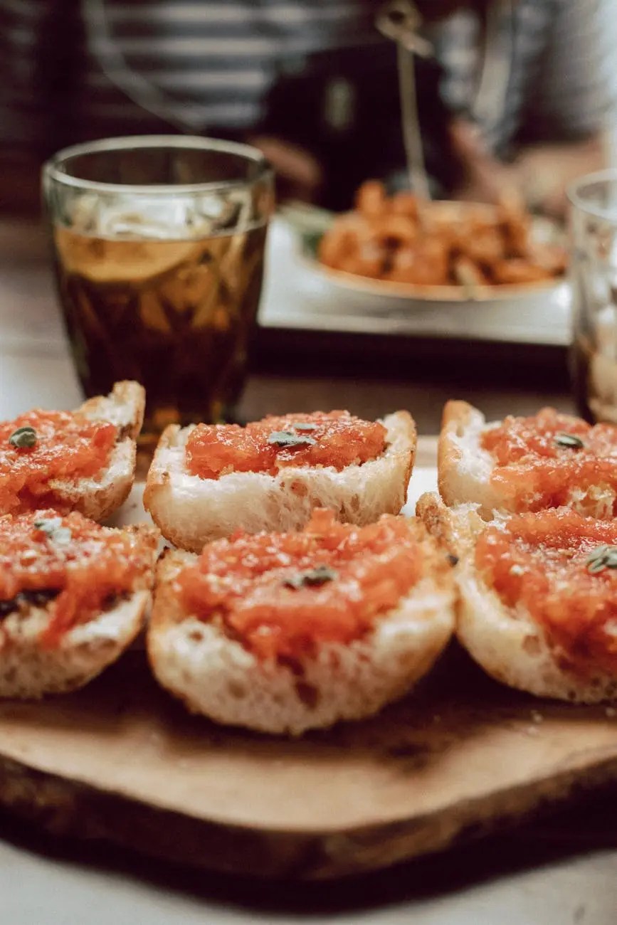 Close-up of toasted bread topped with tomato spread, surrounded by drinks, in a cozy dining setting.