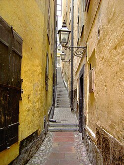 Narrow cobblestone alleyway in Gamla Stan, Stockholm, featuring yellow walls and a vintage lantern.