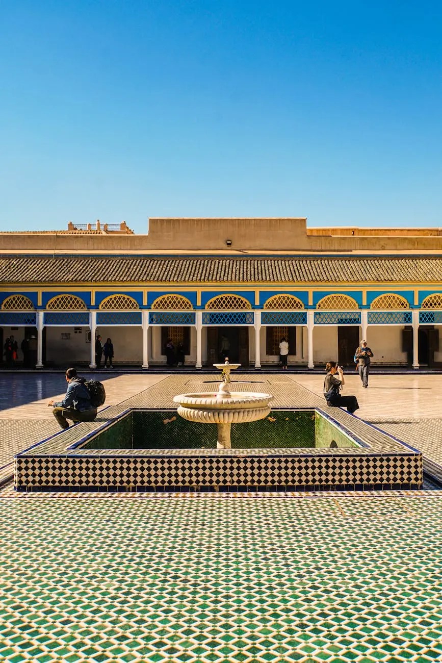 A tranquil courtyard scene in Marrakech featuring a decorative fountain surrounded by intricate tile work and historic architecture under a clear blue sky.