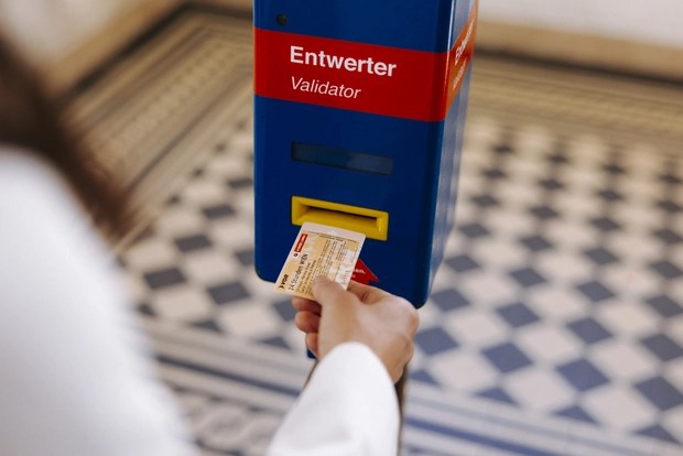 A person using a ticket validator machine with a public transport ticket in Vienna, Austria.