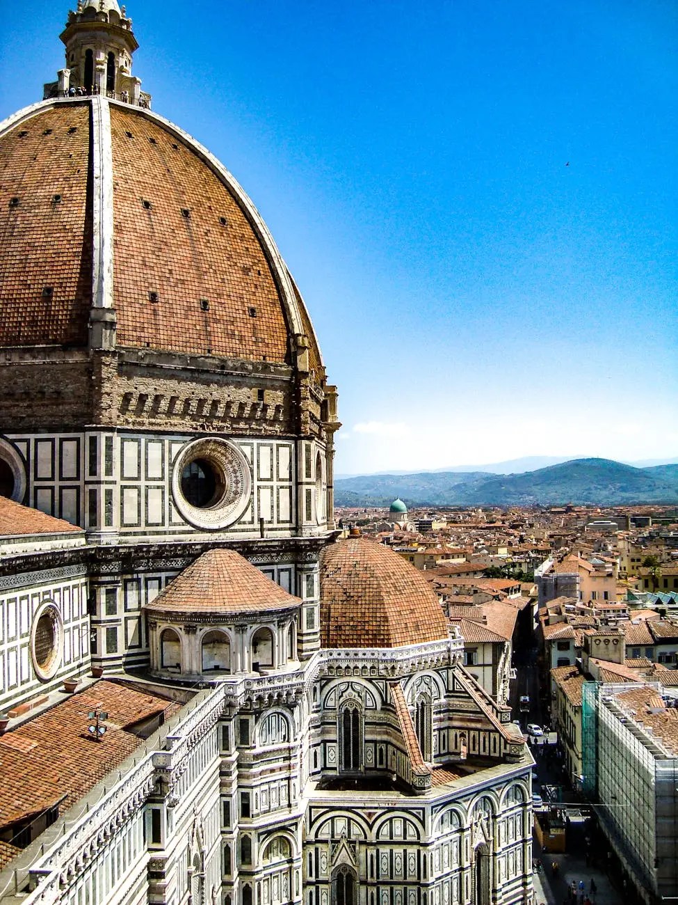 A panoramic view of Florence showcasing the intricate architecture of the Florence Cathedral and its iconic dome against a clear blue sky.