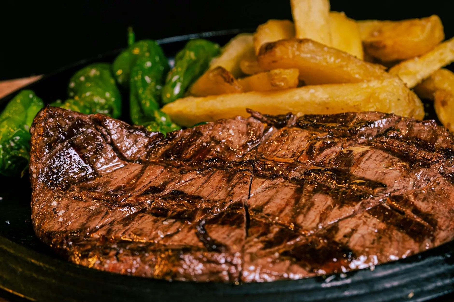 A close-up image of a perfectly grilled Bistecca alla Fiorentina, a traditional Florentine T-bone steak, served with green peppers and golden fries.