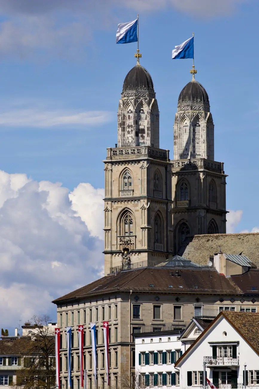 The iconic twin towers of Grossmünster Church in Zurich, Switzerland, against a backdrop of blue sky and fluffy clouds.