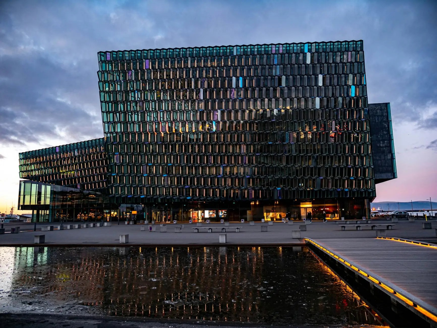 The Harpa Concert Hall in Reykjavik, Iceland, featuring modern glass architecture reflecting the evening sky and surrounding water.