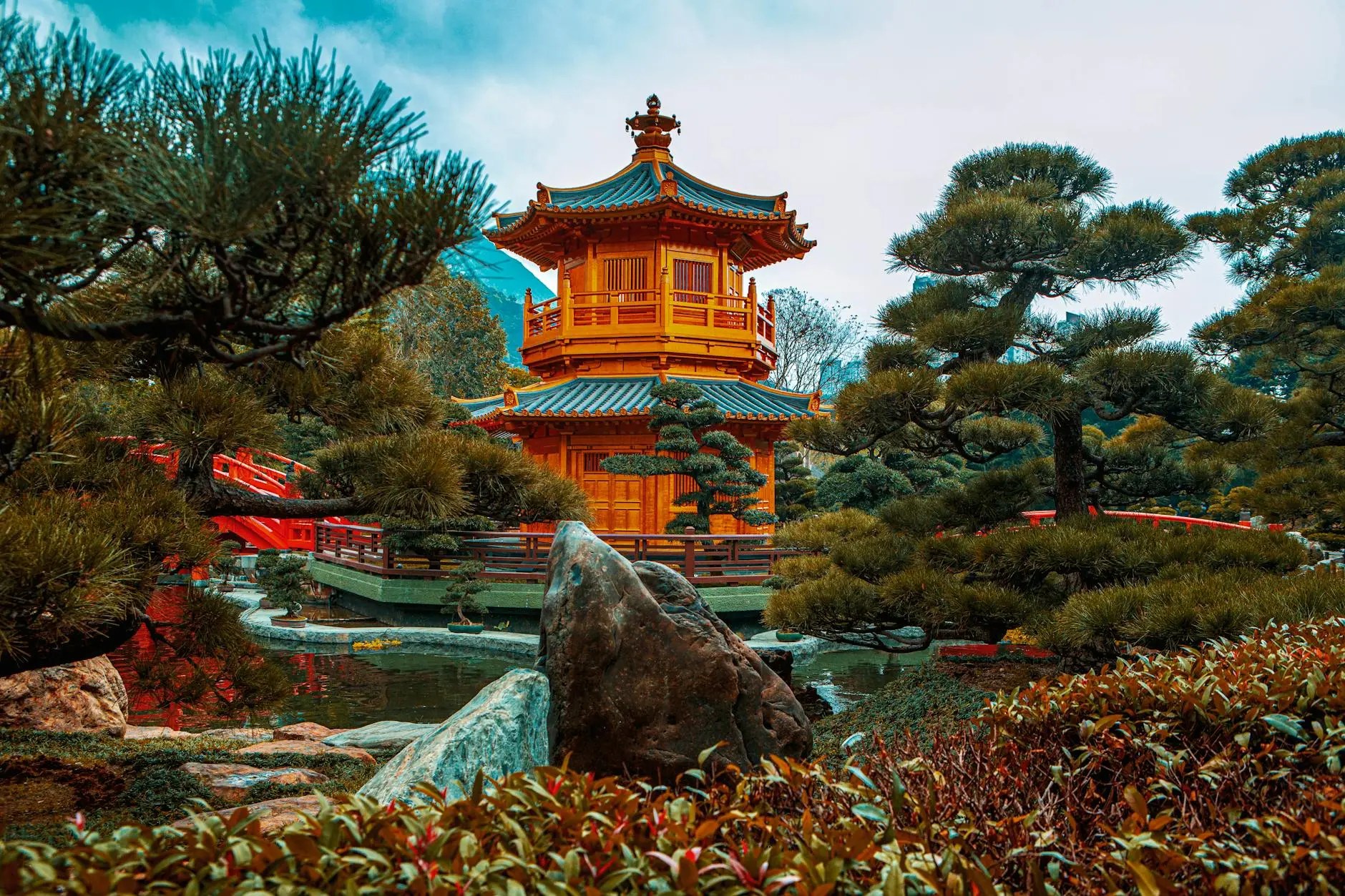 A beautifully designed traditional Chinese pavilion surrounded by lush greenery and tranquil waters, showcasing a serene landscape.