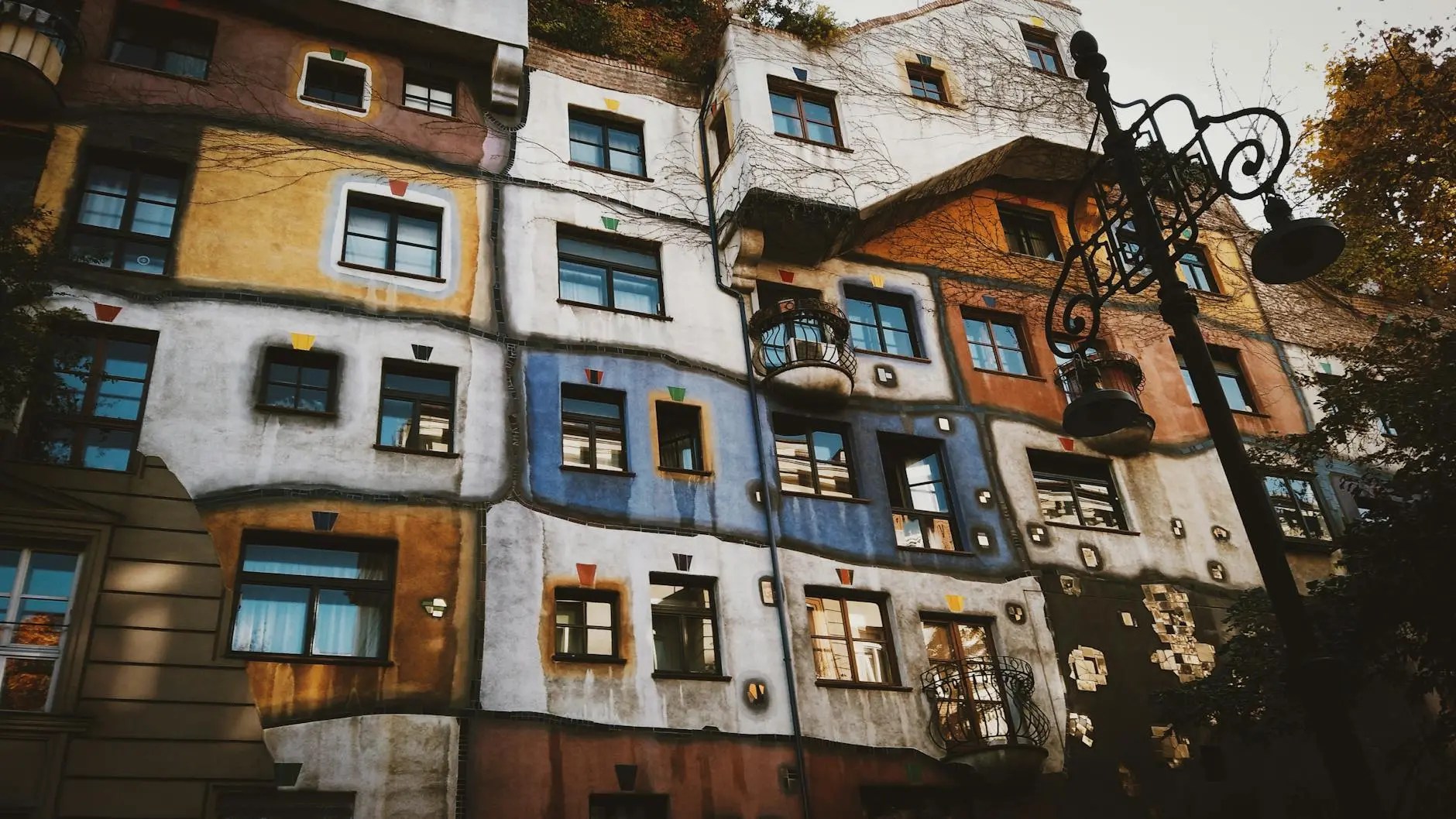 Colorful facade of the Hundertwasserhaus, an architectural landmark in Vienna, featuring irregular shapes, vibrant colors, and unique window designs.