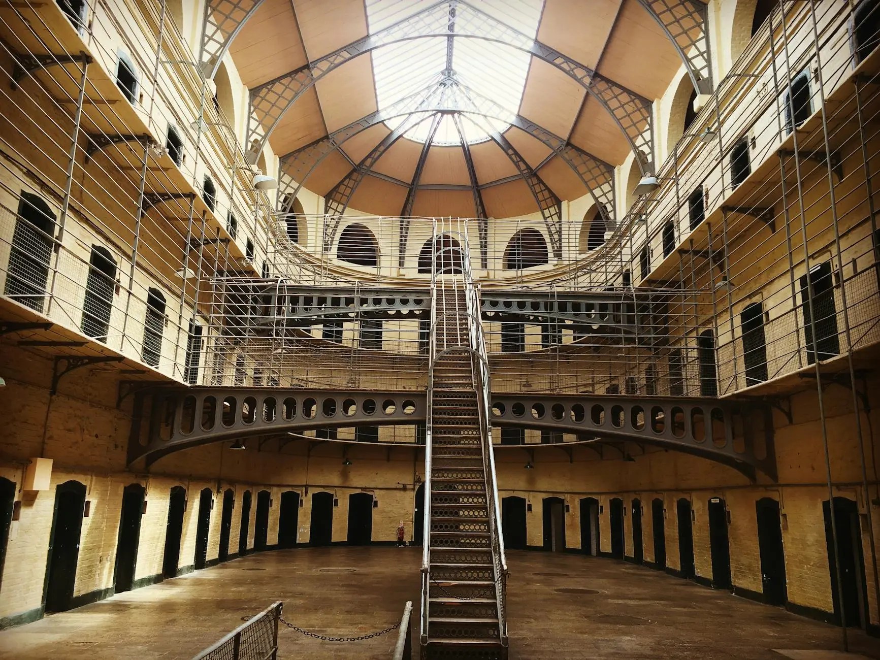 Interior of Kilmainham Gaol, showcasing the spiral staircase and high arched ceiling with natural light illuminating the space.