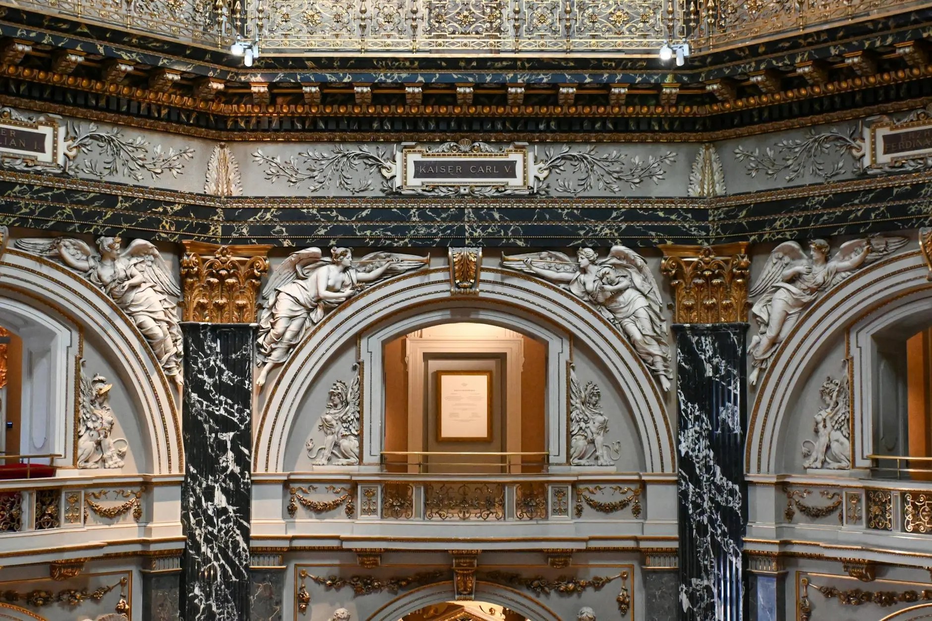 Intricate architectural detail of a hallway at the Kunsthistorisches Museum in Vienna, showcasing ornate sculptures and gold accents.