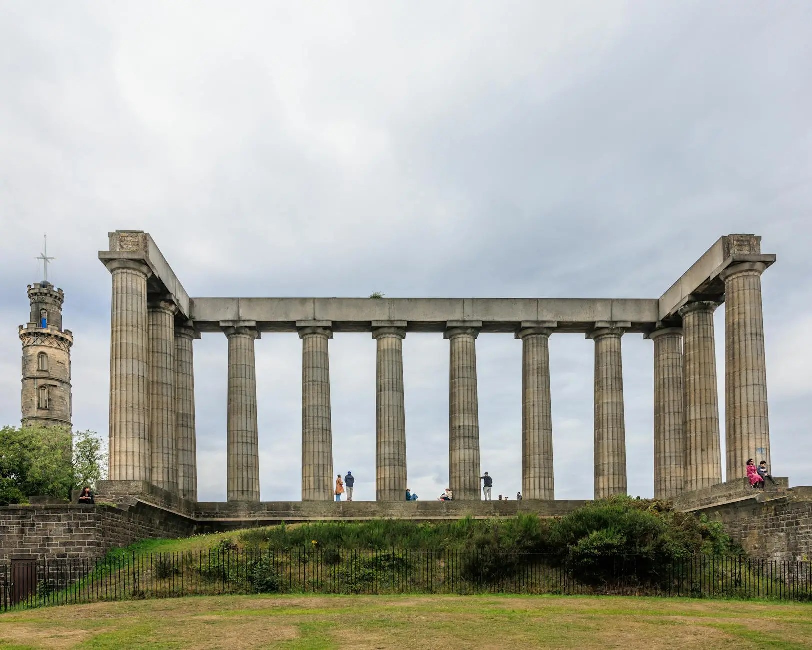 View of the National Monument of Scotland on Calton Hill, Edinburgh, featuring grand columns and a stone tower in the background.