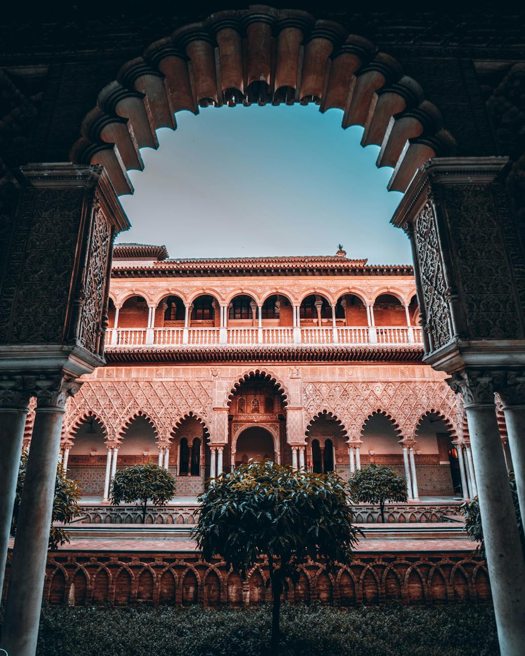 View of the intricate arched architecture and courtyards of the Real Alcázar in Seville, featuring lush greenery and ornate details.