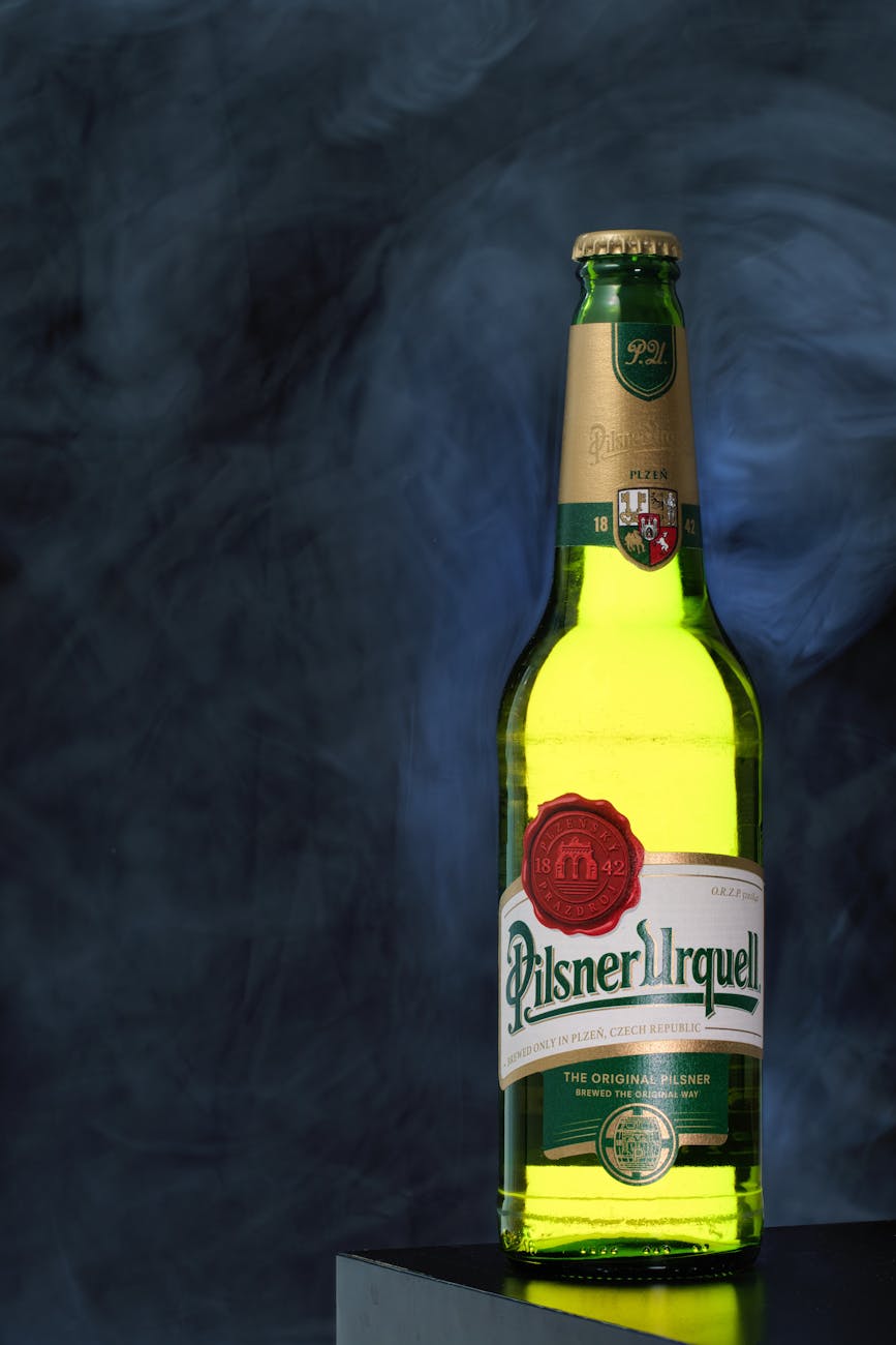 A bottle of Pilsner Urquell beer on a dark background.