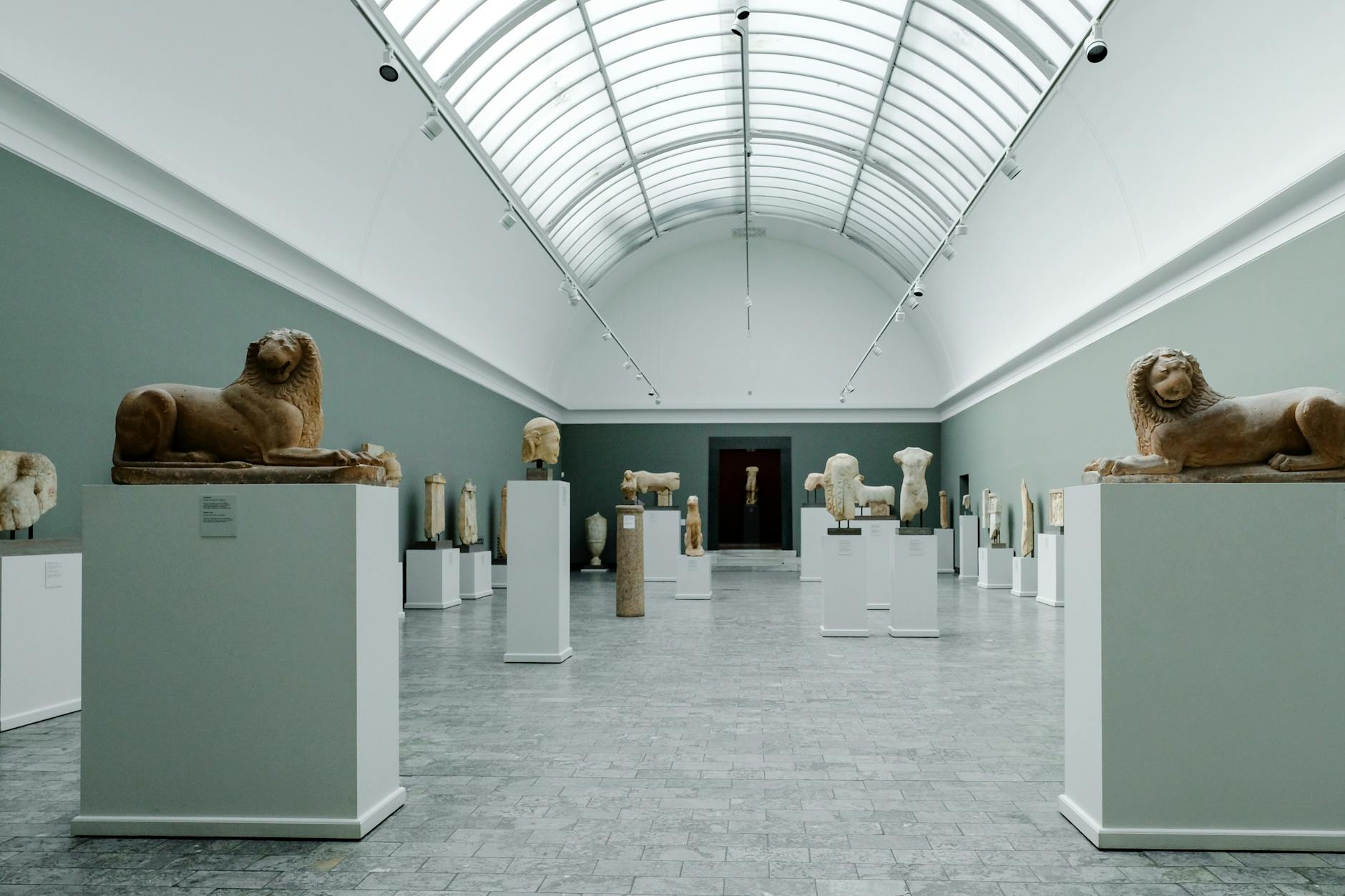 Interior view of an art museum showcasing sculptures, including lion figures and various ancient artifacts displayed on pedestals.