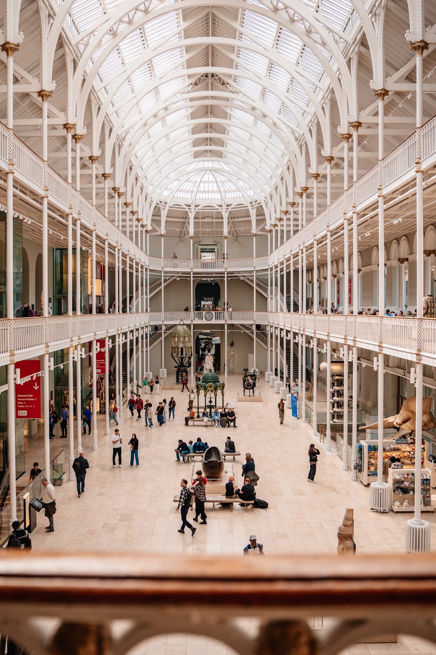 Interior view of the National Museum of Scotland featuring a spacious atrium with high ceilings, natural light, and visitors exploring the exhibits.