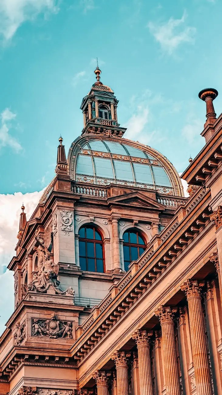 Close-up view of the ornate architectural details of a historical building in Prague, showcasing a decorated dome with a glass top against a blue sky.