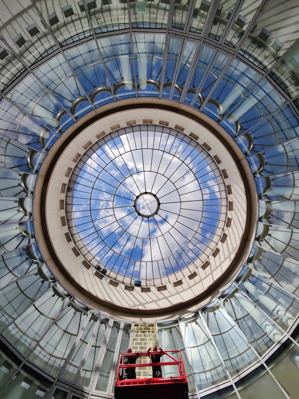 A view from below the glass dome of the Schirn Kunsthalle, showcasing a circular design with reflections and skylights, and two individuals on a platform working above.