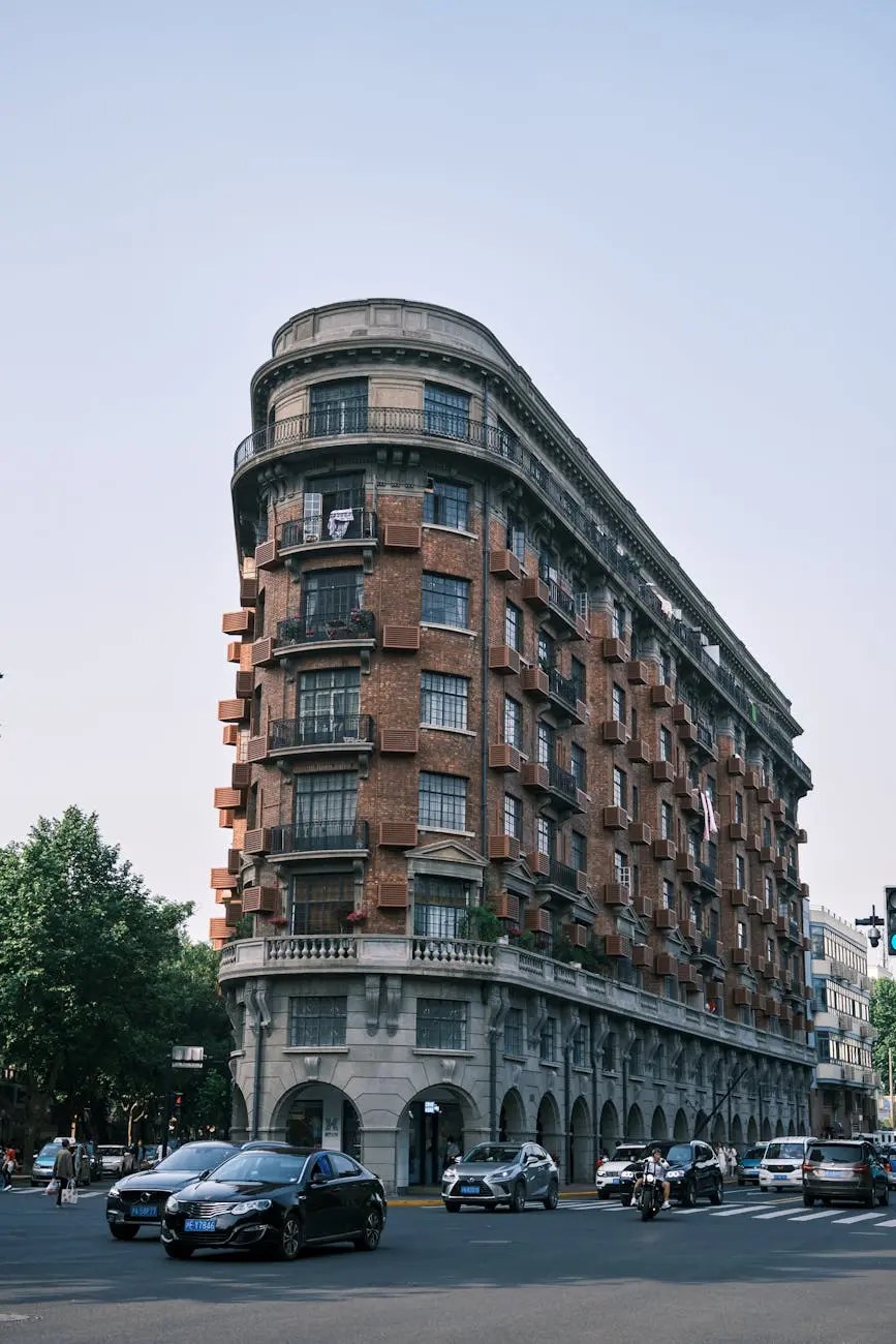 A historic building with a curved facade in Shanghai, surrounded by cars and trees under a clear sky.