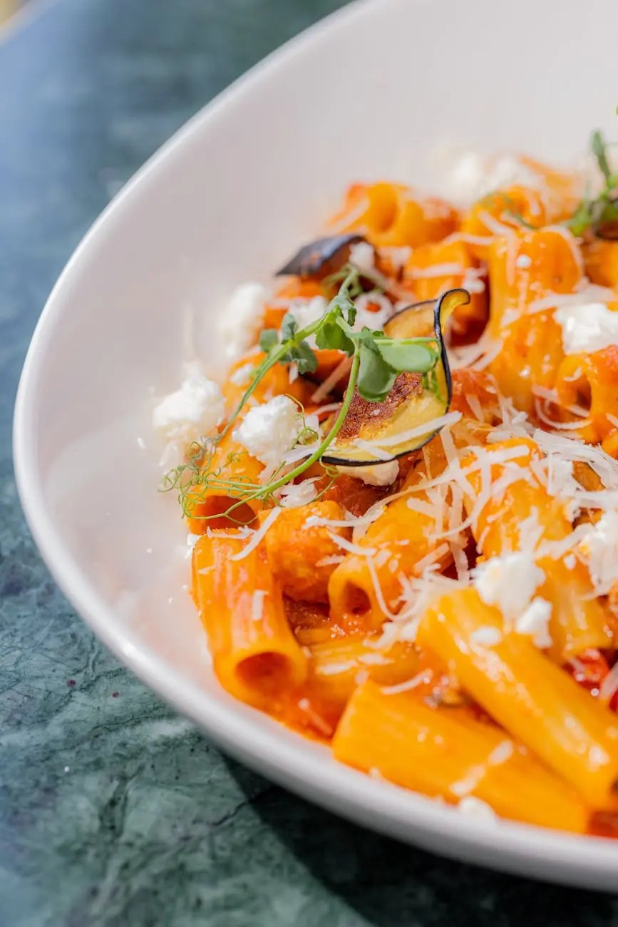 Close-up of a plate of pasta with a rich tomato sauce, topped with grated cheese and fresh herbs.