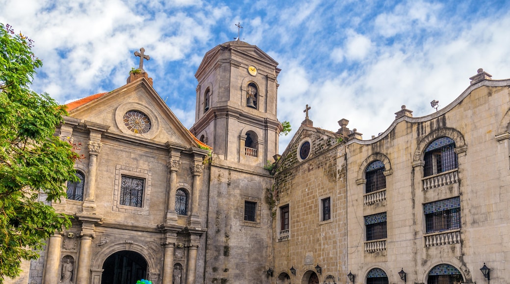 Historic church buildings in Intramuros, Manila, showcasing colonial architecture with intricate details and a blue sky backdrop.