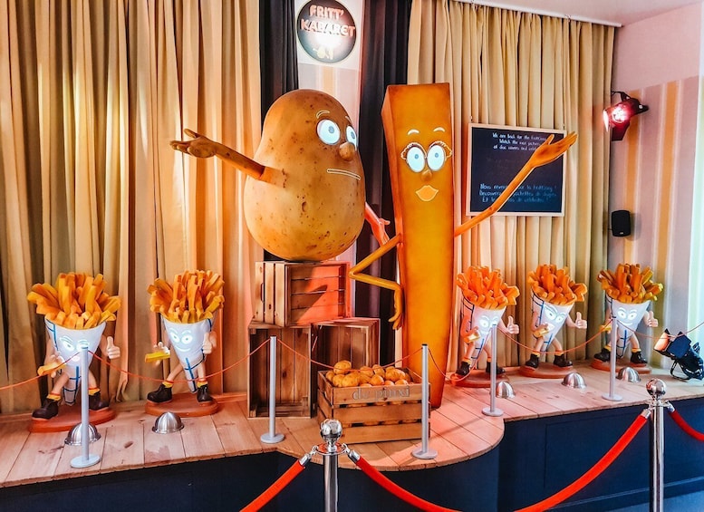 A whimsical display featuring a large animated potato and a French fry character, along with smaller fry characters, set against a backdrop of colorful curtains.