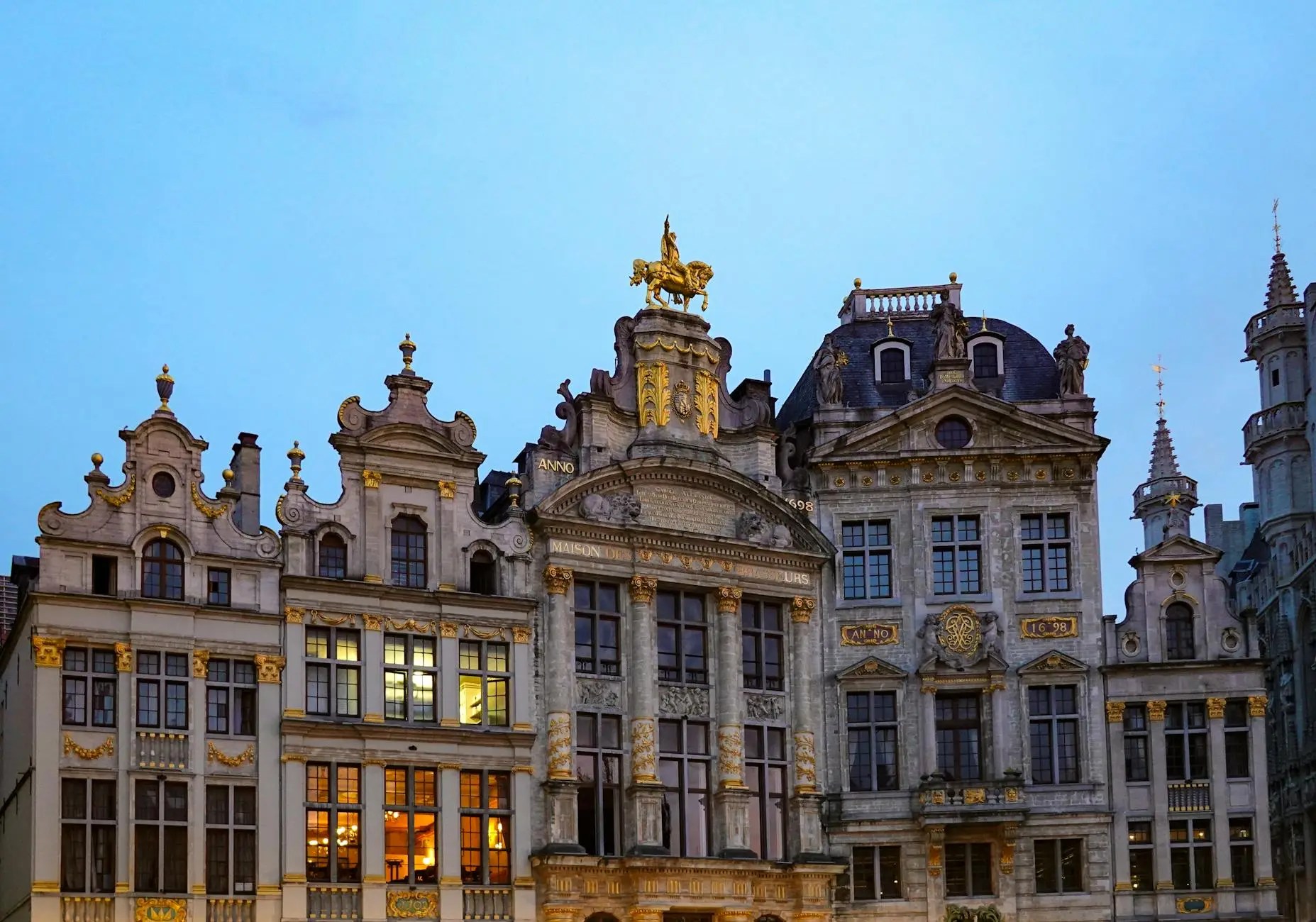 Historic buildings in Grand Place, Brussels, illuminated at dusk, showcasing intricate architecture and golden accents.