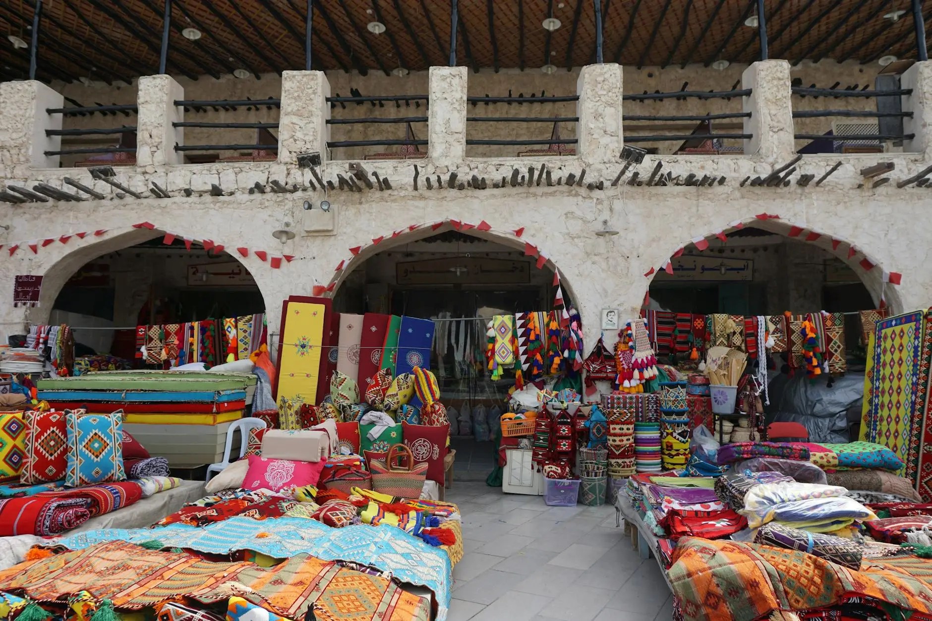 A vibrant display of colorful textiles and traditional crafts at Souq Waqif in Doha, Qatar, showcasing intricate patterns and designs.