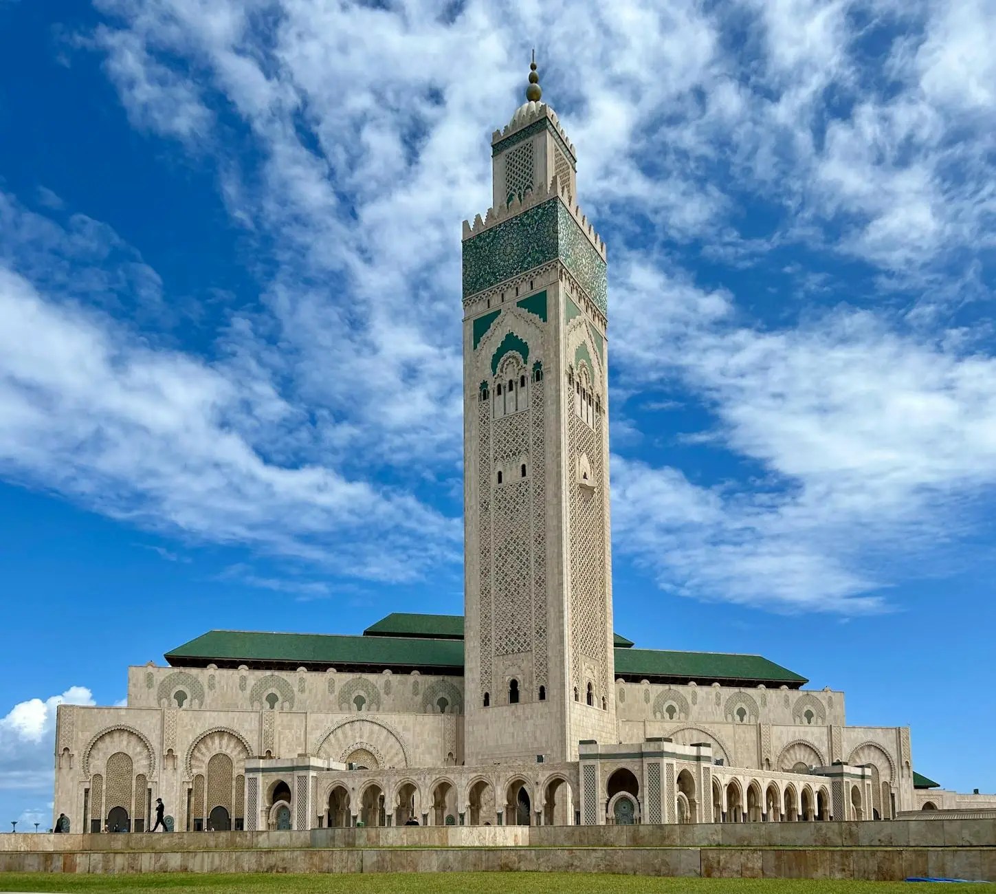 Hassan II Mosque in Casablanca, featuring intricate tilework and a tall minaret against a blue sky.