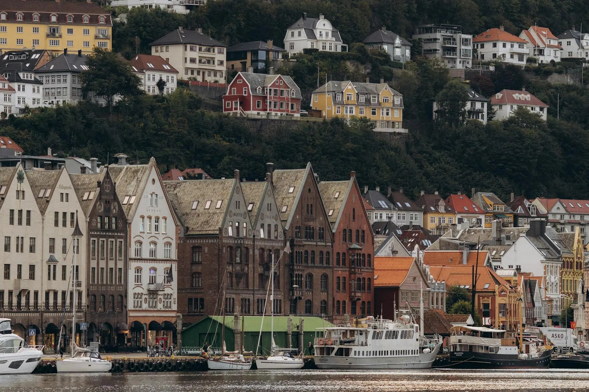 Colorful historic buildings lining a waterfront in Oslo, Norway, with boats docked in the foreground.