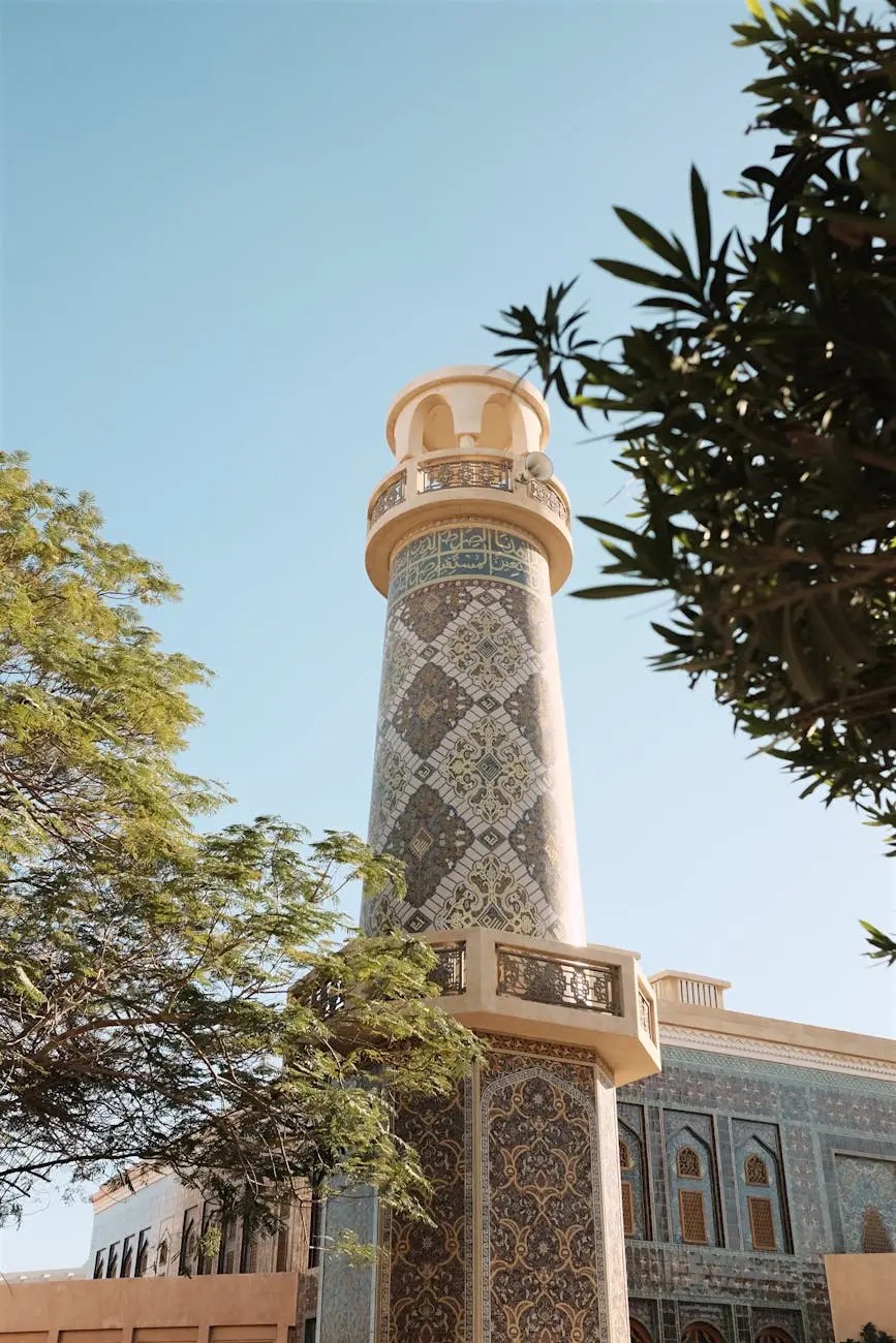 A beautifully patterned tower surrounded by greenery, under a clear blue sky in Doha, Qatar.