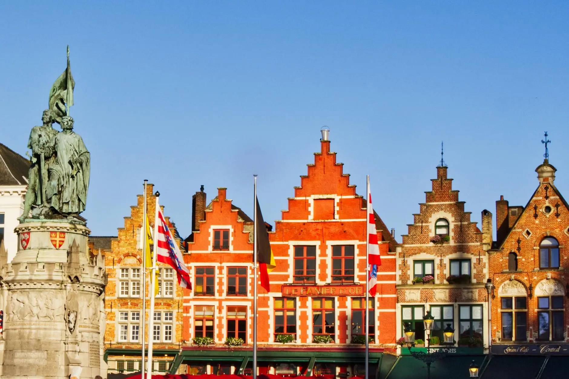 Colorful medieval buildings with gabled roofs and flags in the historic center of Bruges, Belgium.