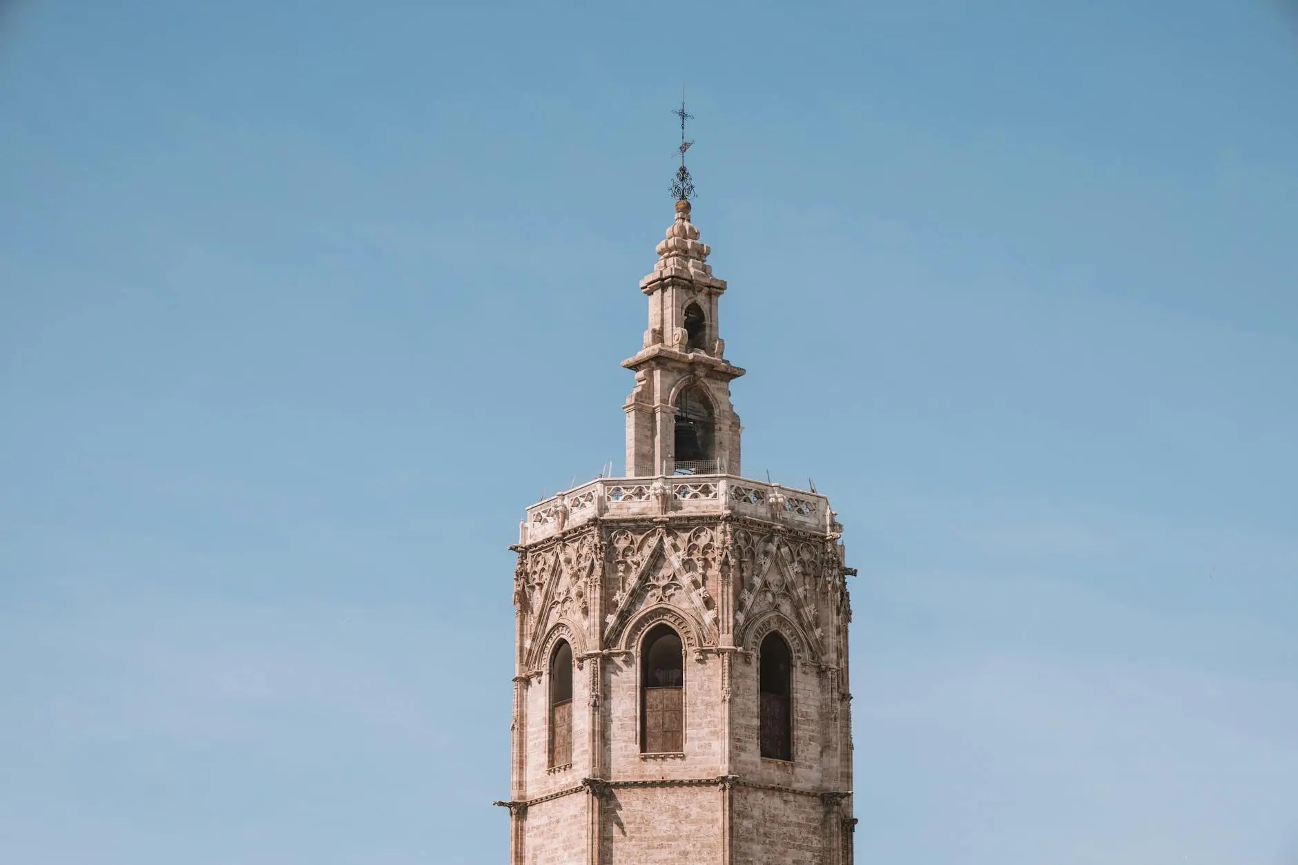 The top of a historic stone tower against a clear blue sky.