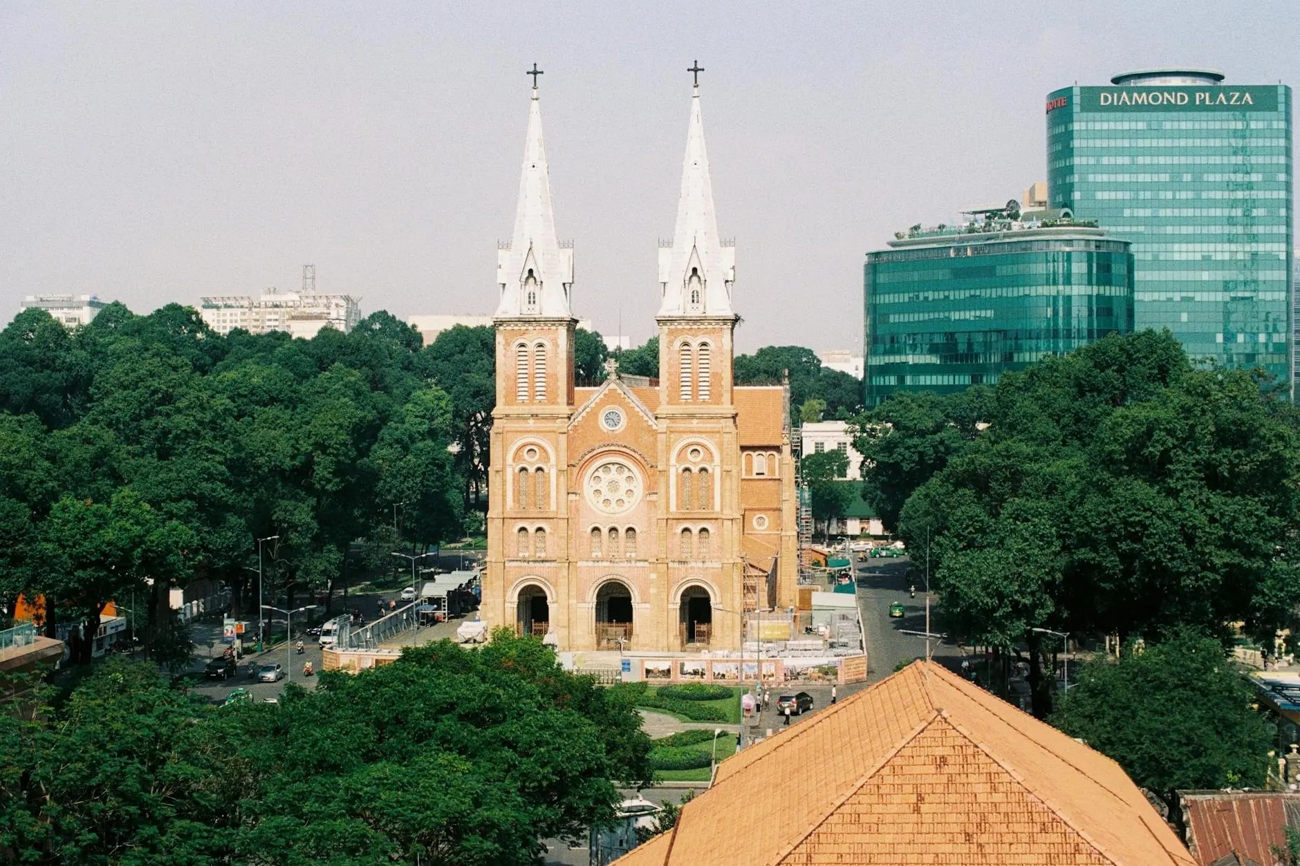 Aerial view of Notre Dame Cathedral in Ho Chi Minh City, surrounded by lush trees and modern buildings.