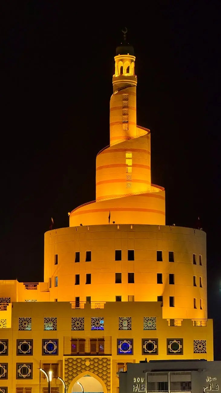 A beautifully illuminated spiral mosque tower at night, showcasing traditional Islamic architectural elements against a dark sky.