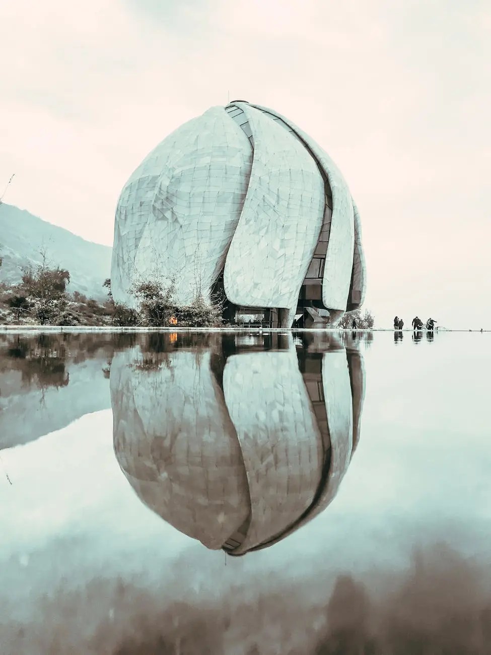 This photograph showcases the breathtaking Bahá'í Temple of South America, an architectural marvel nestled in the foothills of the Andes near Santiago, Chile. Designed by architect Siamak Hariri, the temple is composed of nine immense, independently engineered wings made of cast glass and translucent Portuguese marble. This allows the interior to be bathed in a soft, ethereal light during the day, while the structure appears to emit a gentle glow at night. As one of only nine continental Bahá'í Houses of Worship in the world, it welcomes people of all faiths and backgrounds for personal meditation and prayer, representing a powerful symbol of unity and a must-visit site for its serene beauty and innovative design.