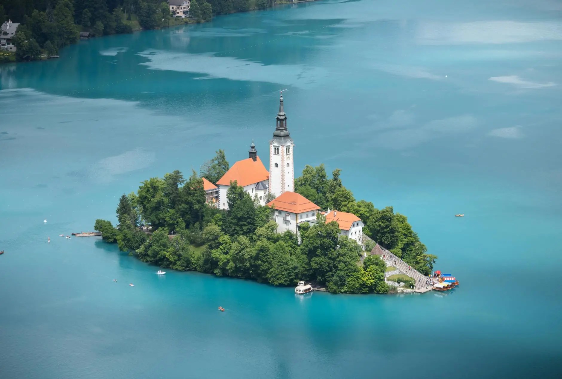 Aerial view of Lake Bled, featuring the iconic church on Bled Island surrounded by lush greenery and turquoise waters.