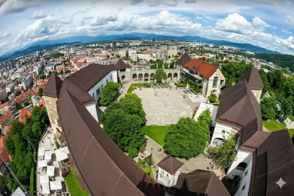 Aerial view of Ljubljana Castle with surrounding greenery, overlooking the city skyline under a cloudy sky.