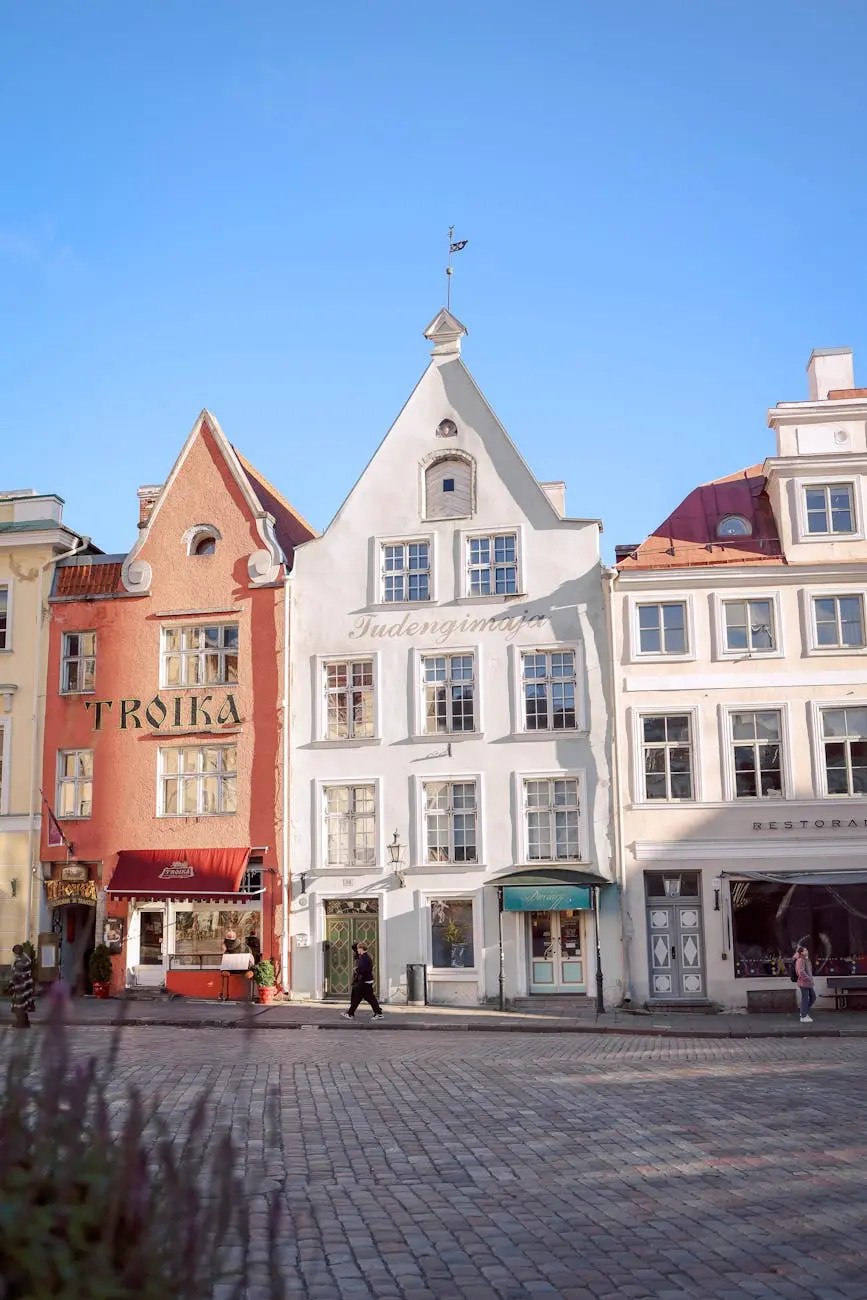 Colorful historical buildings lining a cobblestone street in Tallinn, Estonia, with clear blue skies above.