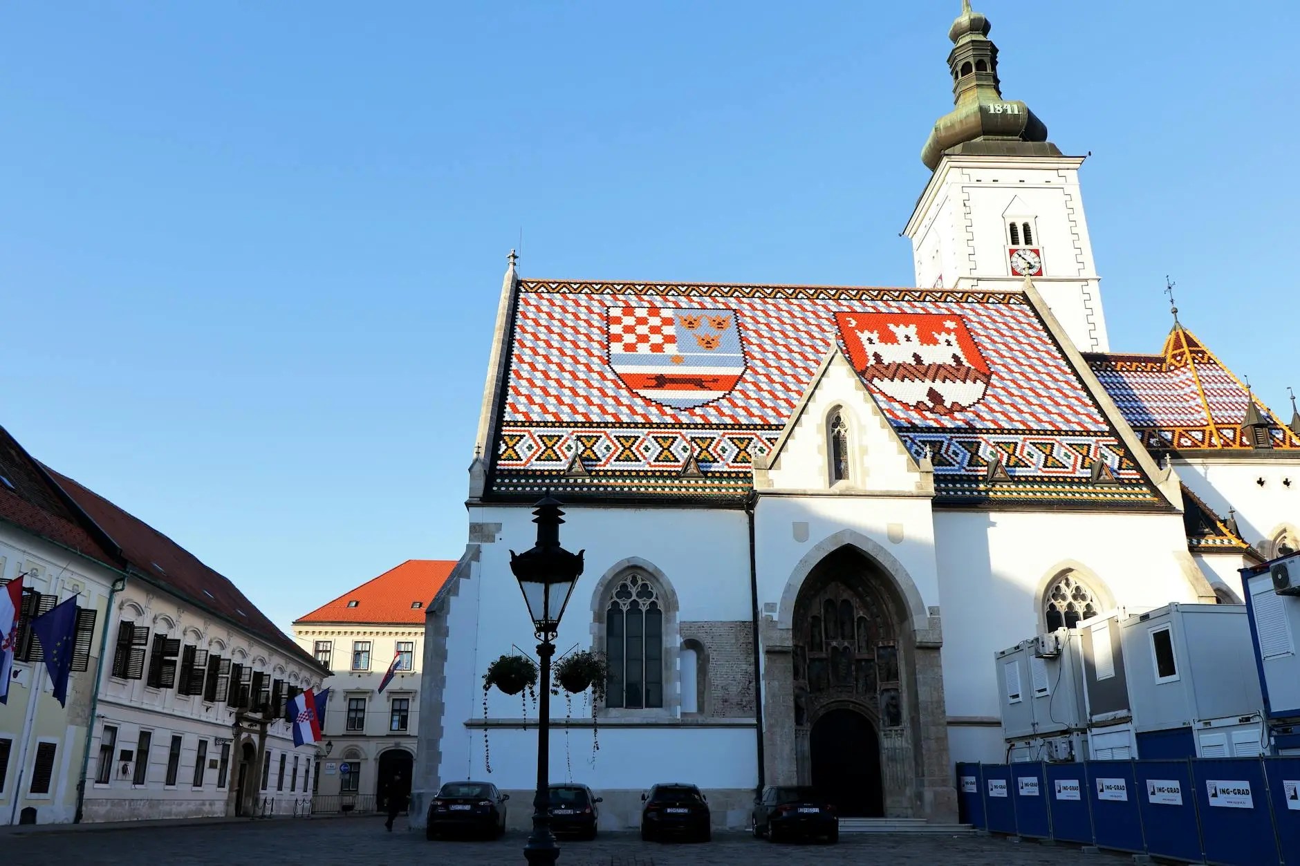 The iconic St. Mark's Church in Zagreb, showcasing a colorful, tiled roof adorned with Croatian coats of arms, set against a clear blue sky.