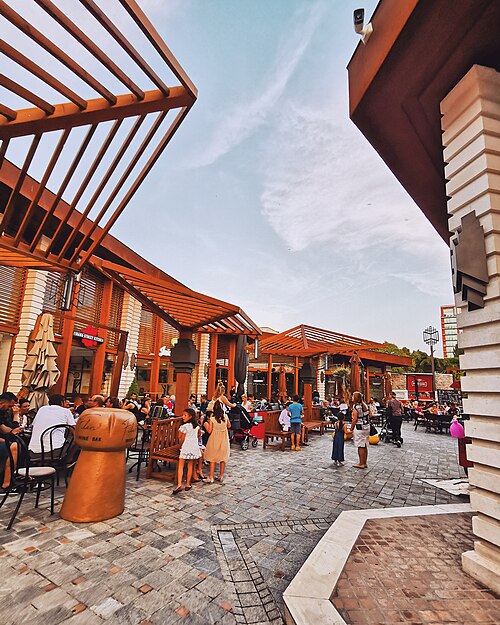 Outdoor café area in Tirana featuring wooden structures and people dining and socializing.