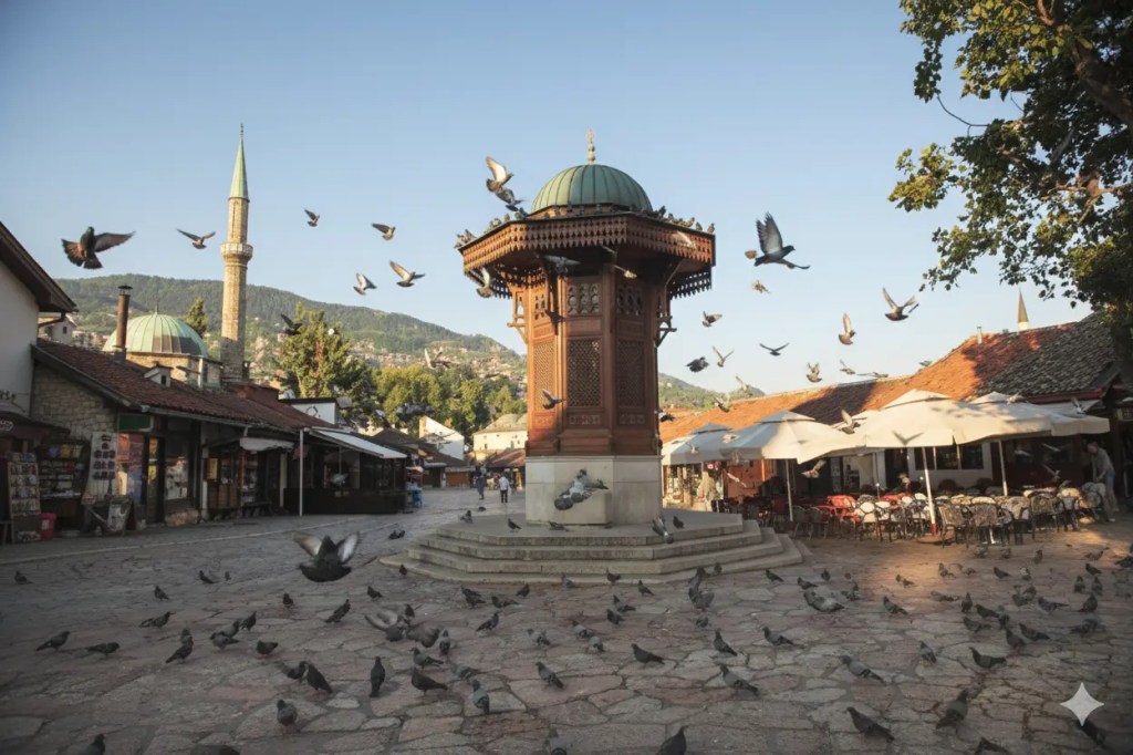 A lively scene at the Sebilj fountain in Baščaršija, Sarajevo, surrounded by rooftops and a mosque, with pigeons taking flight.