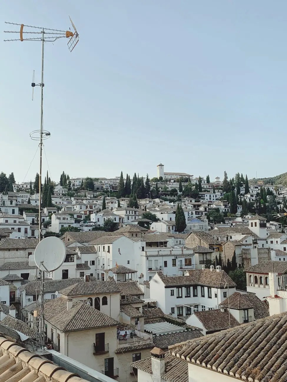 Scenic view of whitewashed houses and terracotta roofs in Granada, Spain, with a clear blue sky.