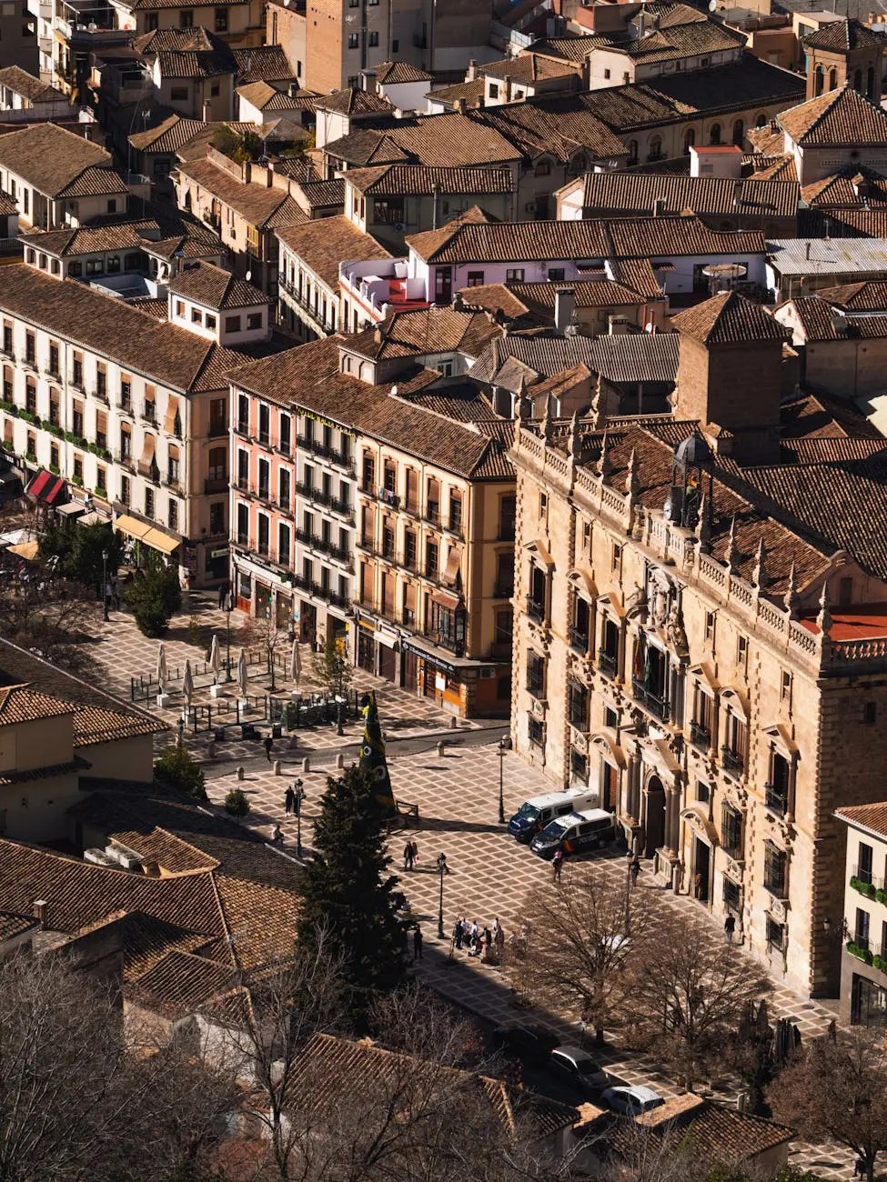 Aerial view of a historic square in Granada, Spain, featuring traditional Spanish architecture, tiled rooftops, and quaint streets lined with shops and cafes.
