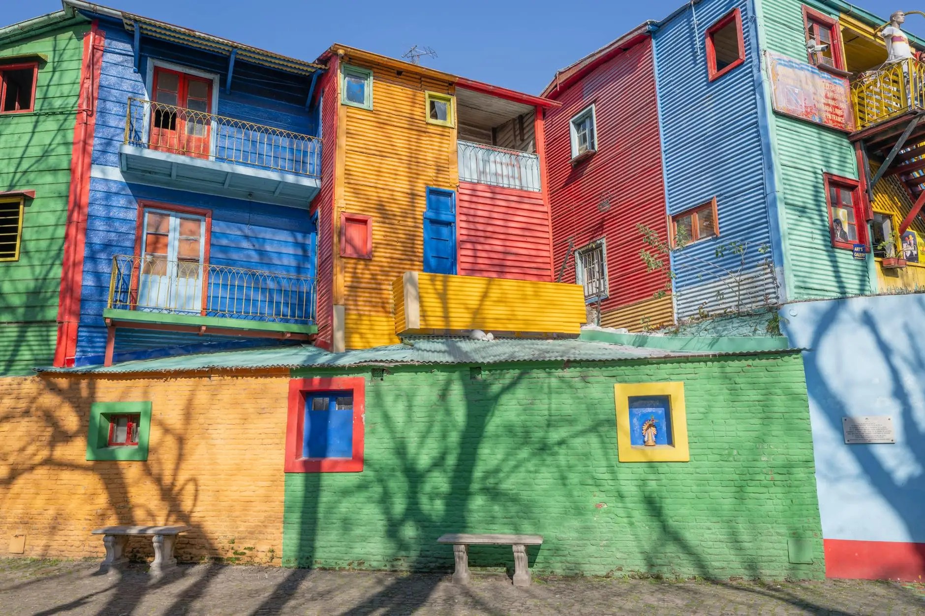 Colorful buildings in a vibrant neighborhood, featuring various shades of blue, green, red, yellow, and orange, with balconies and windows.
